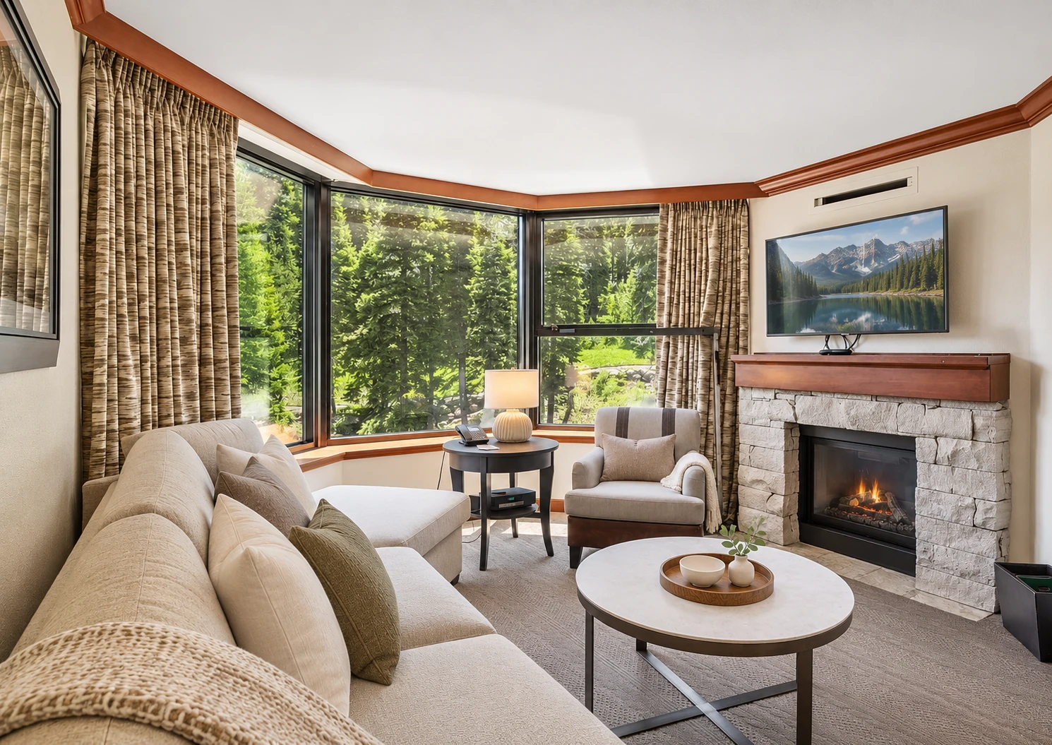 Private two-bedroom corner suite living area with forest-facing corner windows, a fireplace, and queen sleeper sofa; digitally styled linens and accessories
