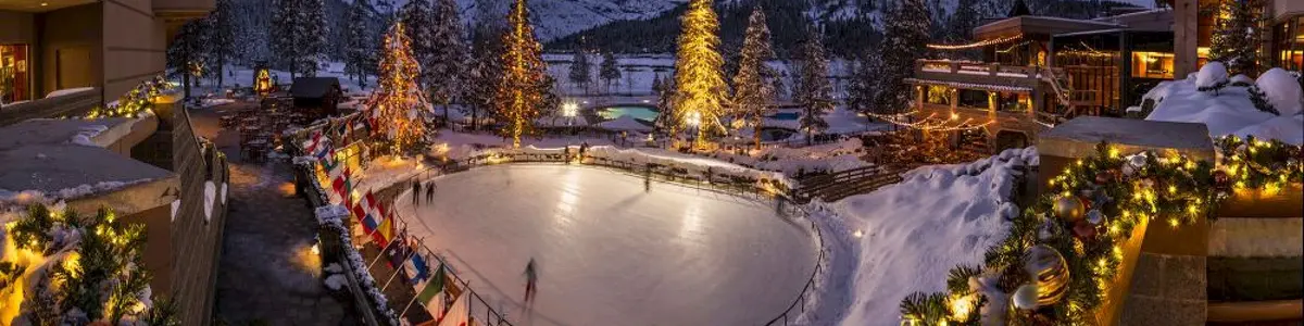 Everline’s outdoor ice rink at dusk, framed by illuminated trees, the resort, and snowy mountains